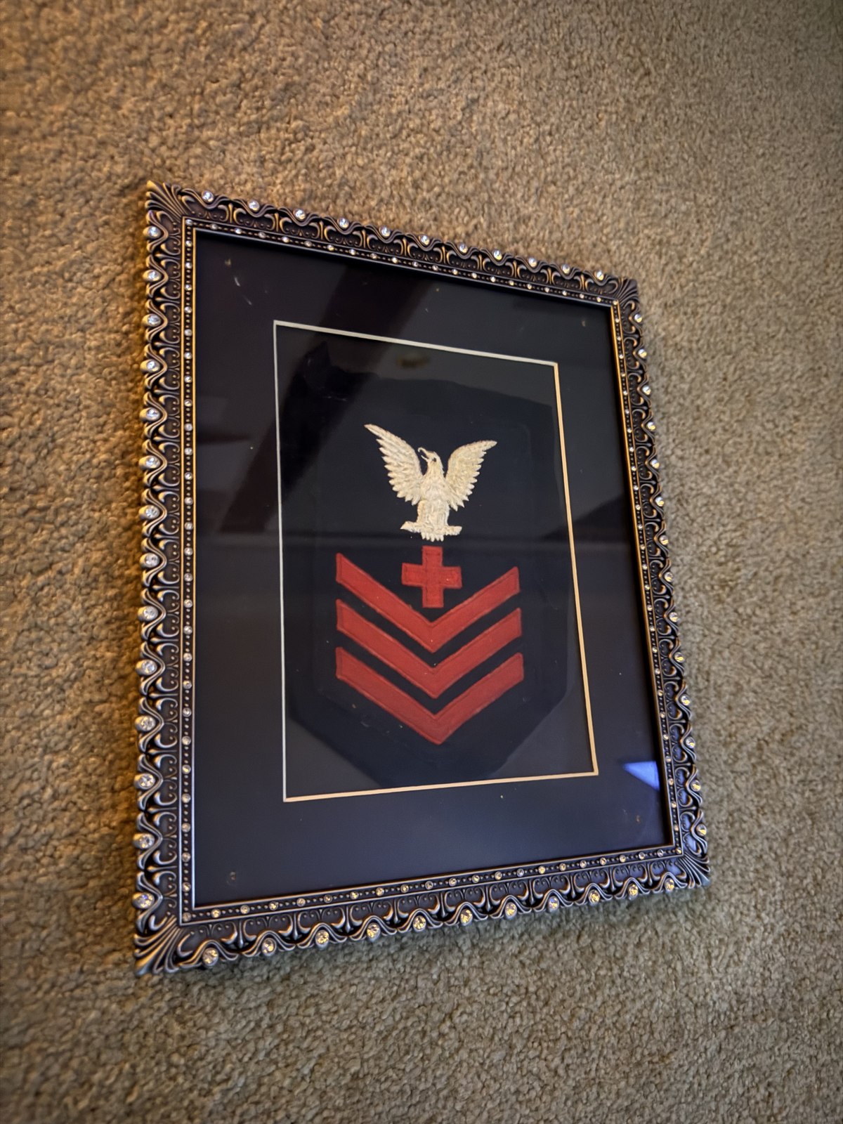 Robert Keith Krotzer's Navy rating badge, framed — eagle and chevrons over a pharmacist's red cross