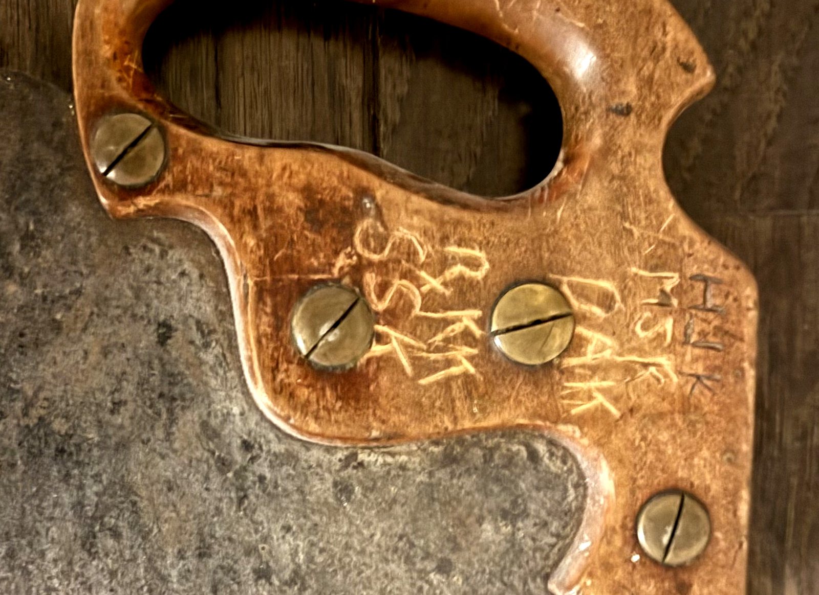 Carved initials and wheat motif on the saw handle